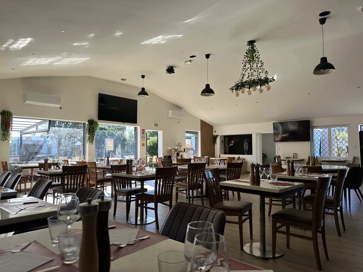 La salle du restaurant, tables dressées sous la charpente claire